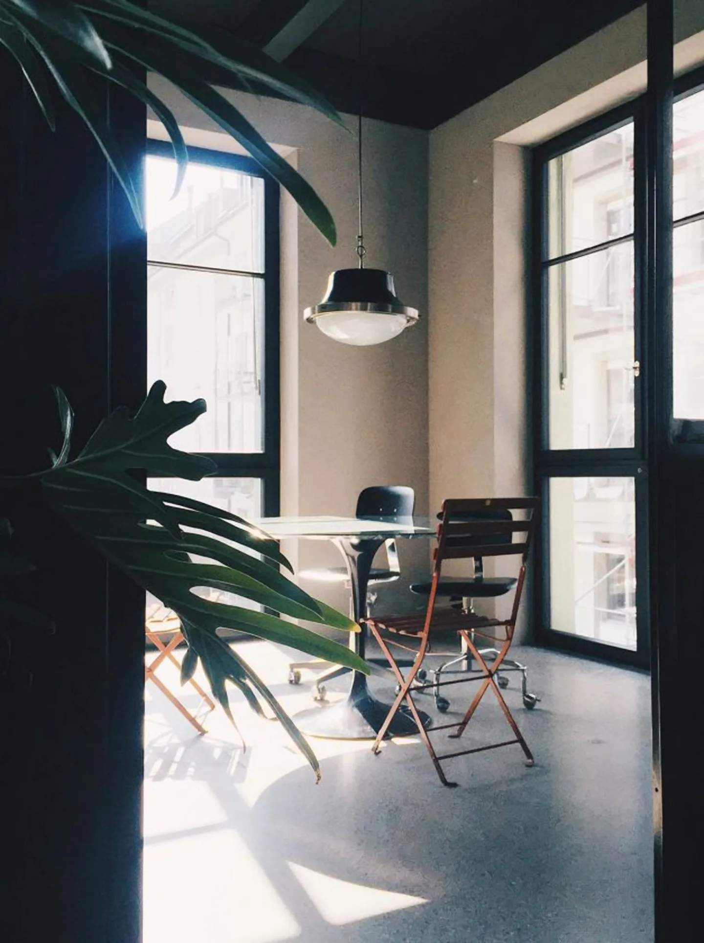 Fensterplatz mit Bistrotisch und Pflanzen im Gegenlicht