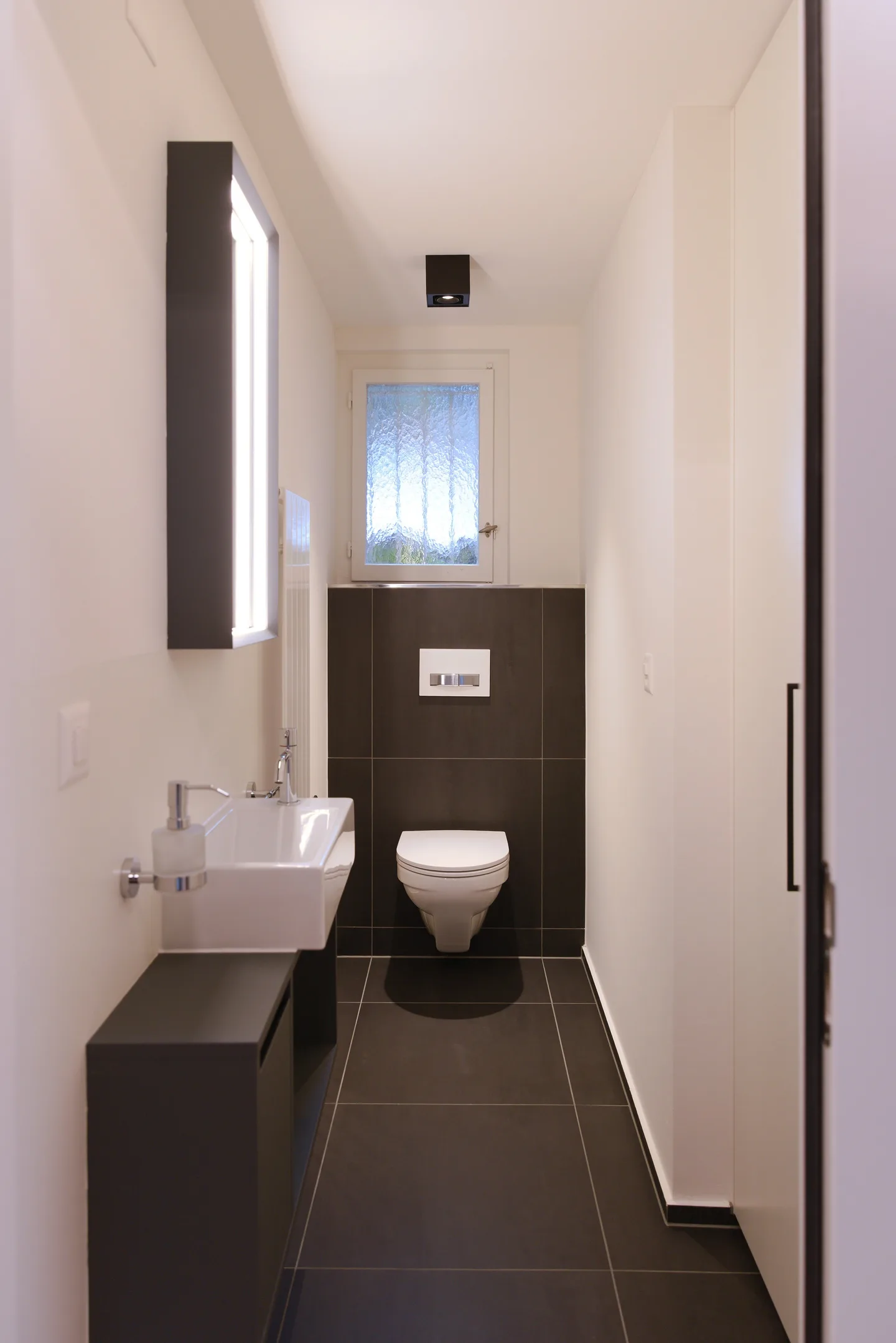 Gäste-WC mit dunklen Platten und Glasbausteinfenster