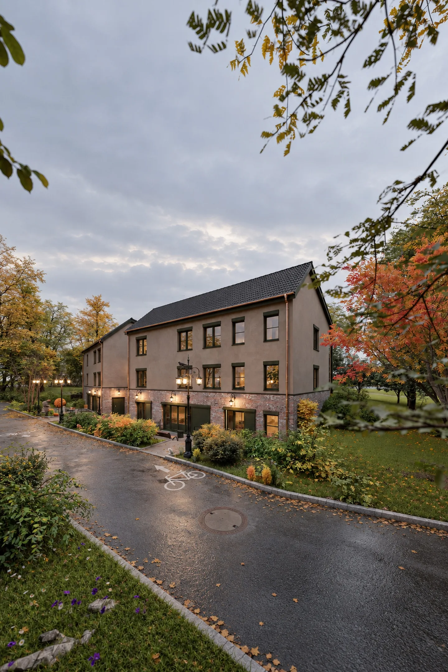 Gesamtansicht am Abend, beleuchtete Fenster und herbstliche Bäume