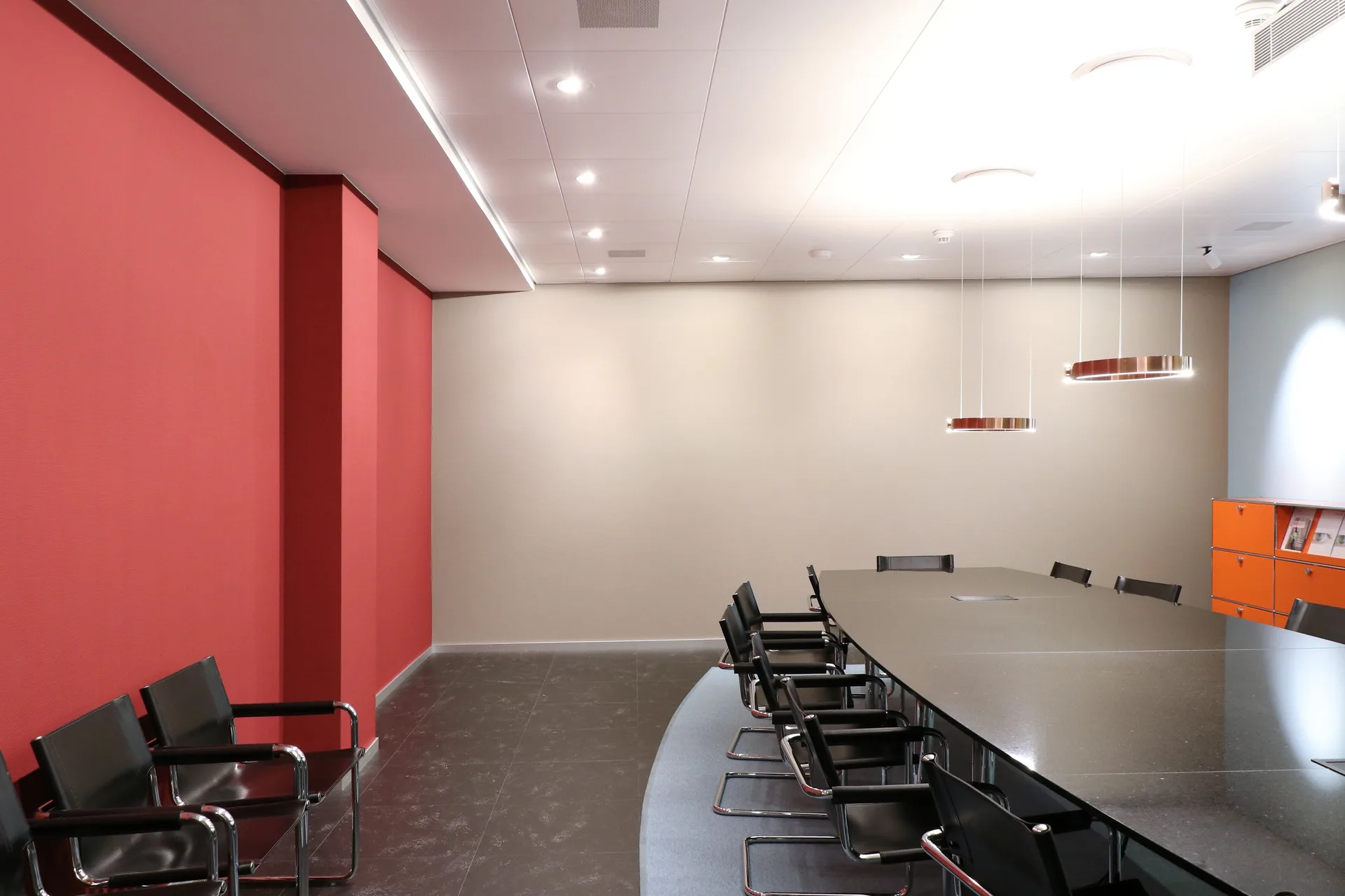 Sitzungszimmer mit ovalem Tisch und roter Stirnwand