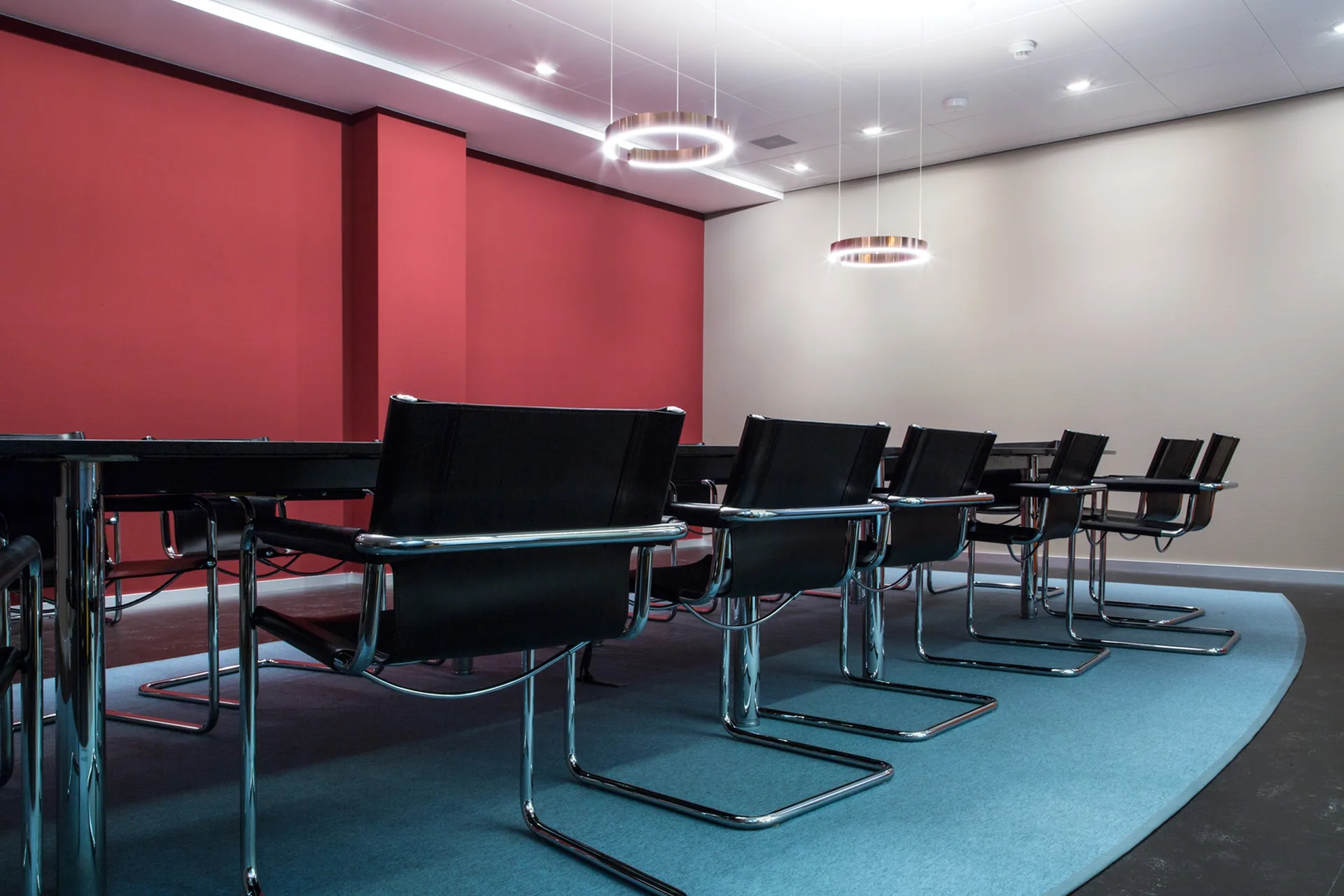 Sitzungszimmer mit langem Tisch, Freischwingern und roter Wand