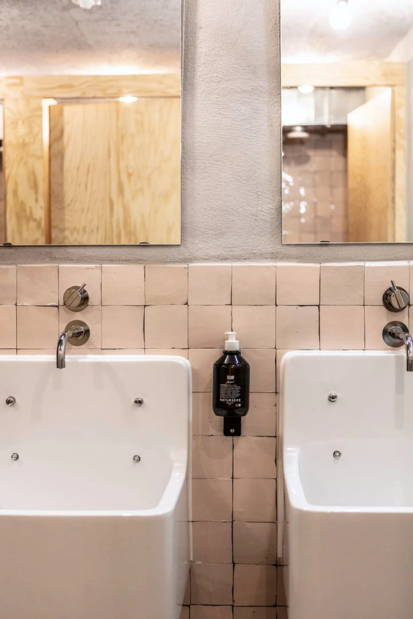 Waschraum mit zwei Becken, hellen Plättli und Holz