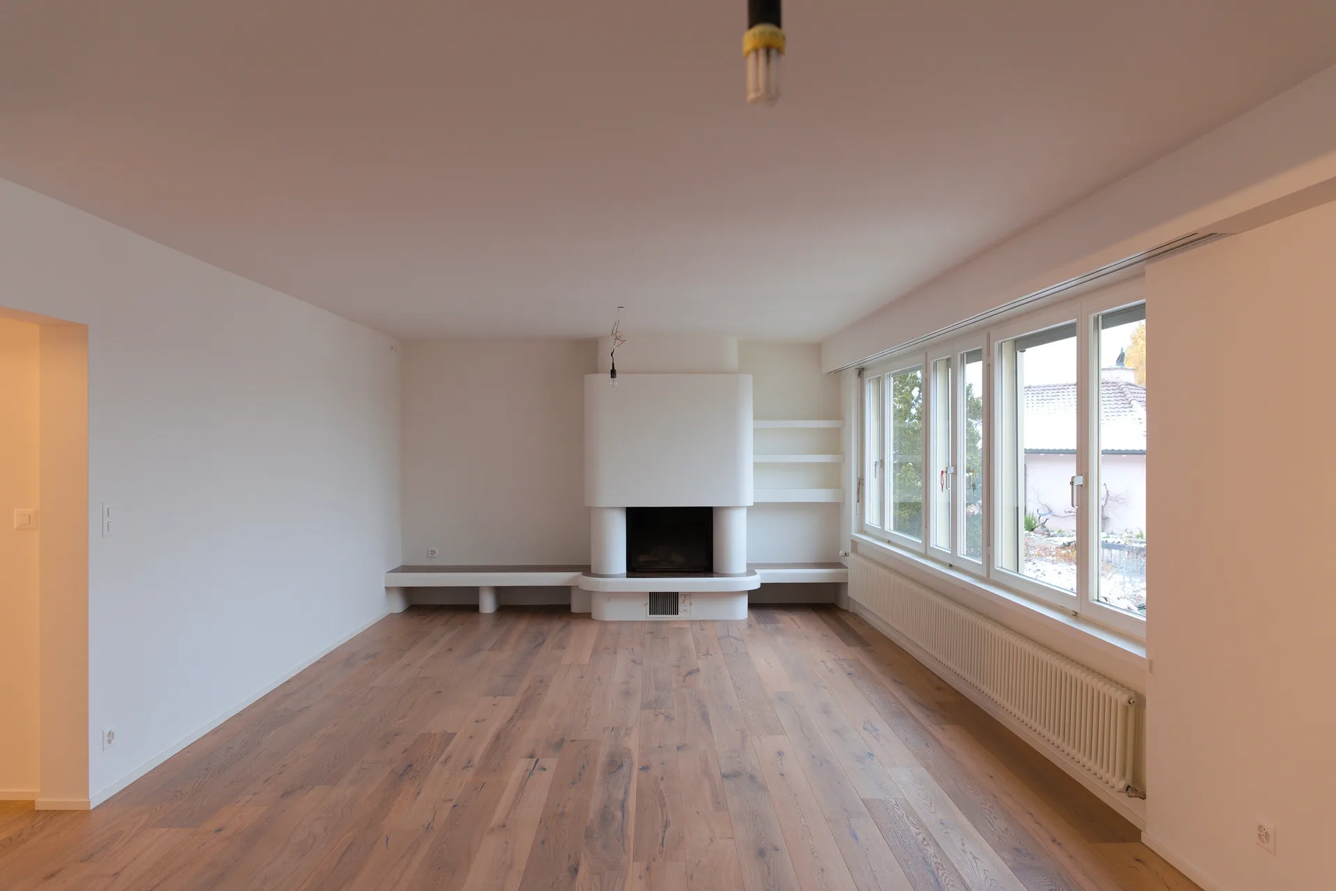Wohnraum mit weissem Cheminée und Sitzbank