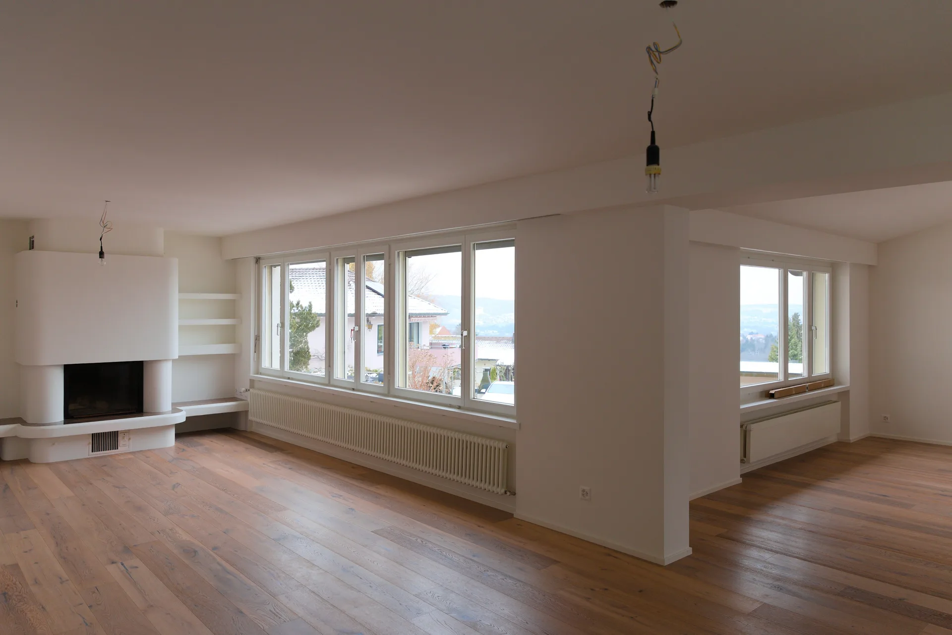 Wohnraum mit Cheminée, Fensterfront und Eichenparkett