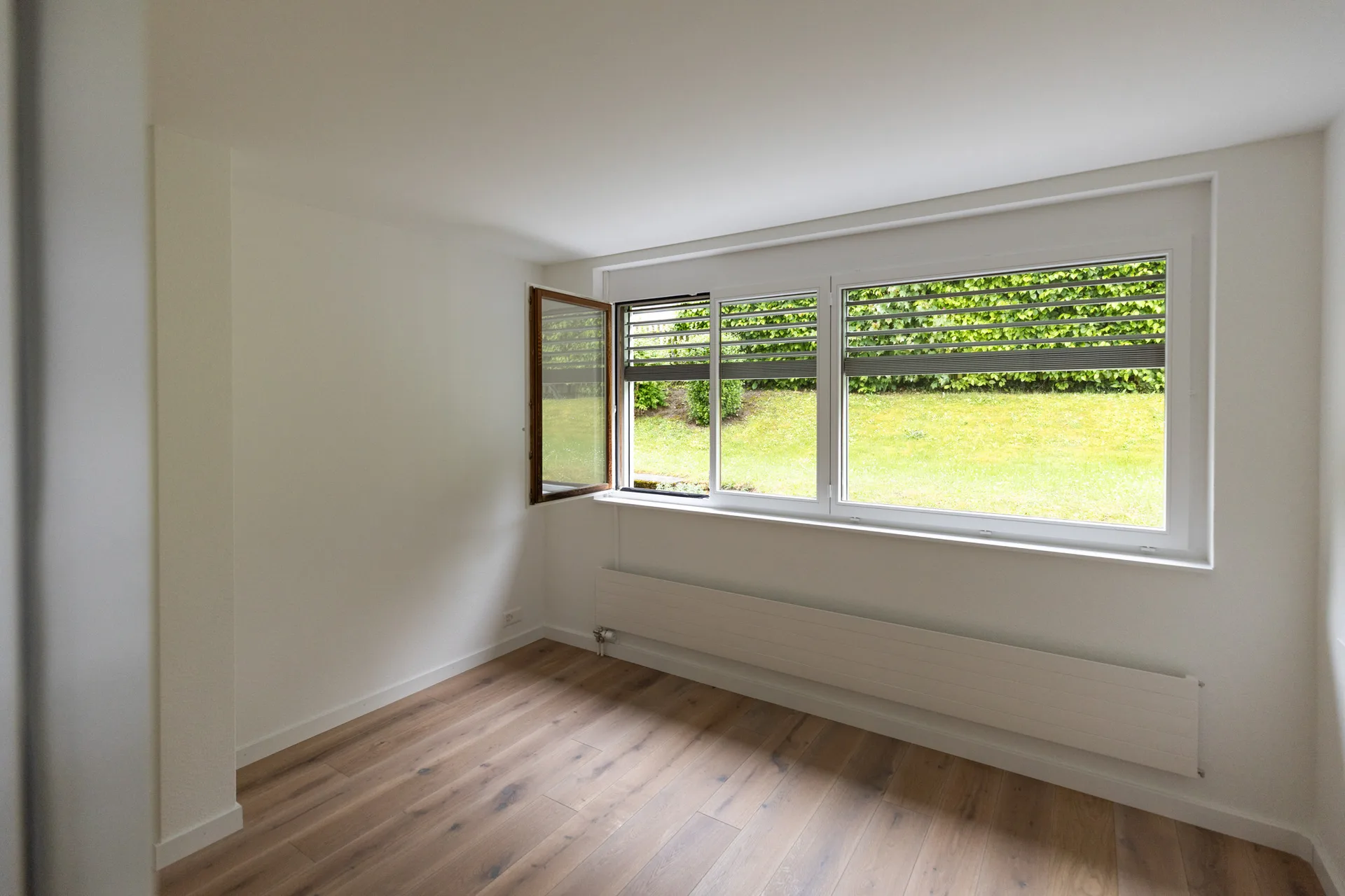 Zimmer mit Fensterband zum Garten und Eichenparkett